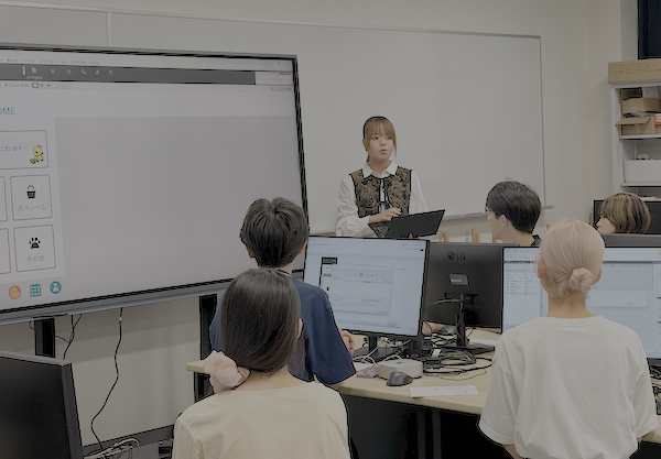 大型モニターの前でプレゼンを行う学生